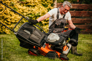 A old man checking red lawn mover repair