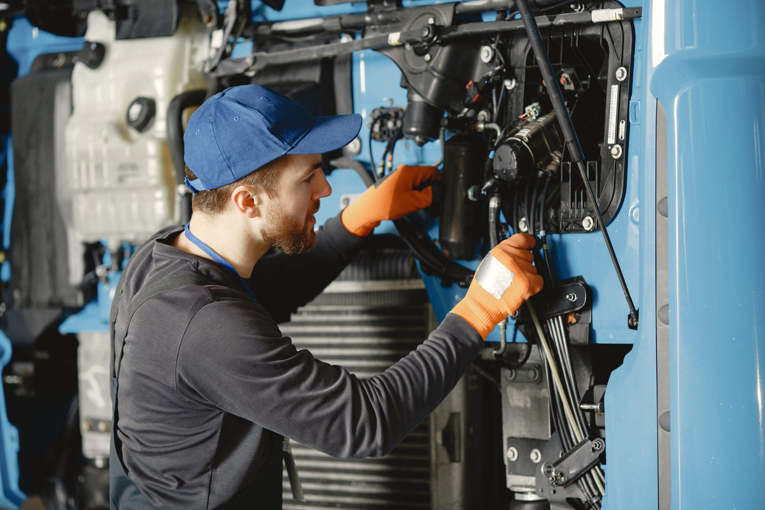 Worker checks quality of truck in garage in uniform working on lawn mower